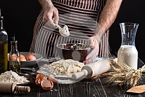 Chef hands are sprinkling flour into bowl to make dough.