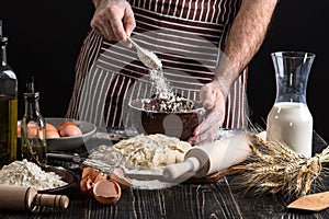 Chef hands are sprinkling flour into bowl to make dough.