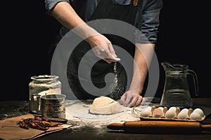 Chef hands are sprinkling a flour powder on dough