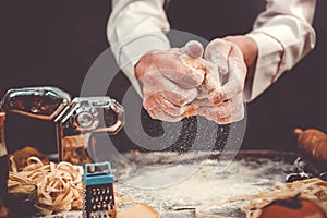 Chef hands working with dough. Flour is poured on the table.