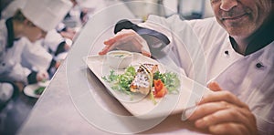 Chef happy with finished dish with trainees working in kitchen