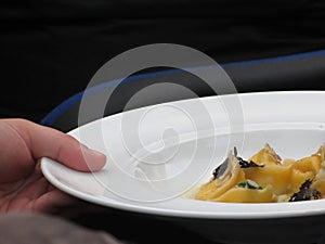 Chef holding cooked handmade Agnolotti to serve in the restaurant . Typical italian egg pasta on white plate