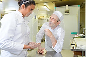 Chef holding dough giving advice to apprentice