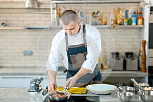 Chef holding frying pan. Chef is stirring dish in frying pan at professional kitchen. Preparation of european food.