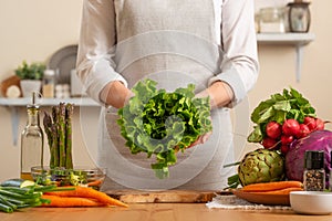 The chef is holding a green lettuce in the form of a heart. The concept of losing healthy and wholesome food, detox, vegan eating