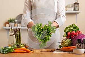 The chef is holding a green lettuce in the form of a heart. The concept of losing healthy and wholesome food, detox, vegan eating