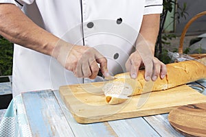 Chef holding knife cutting slide bread making on wooden board