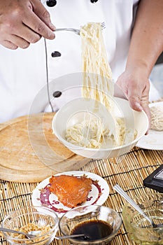 Chef holding the noodle from the bowl with fork
