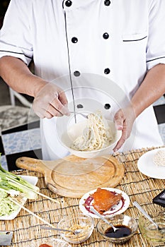 Chef holding the noodle from the bowl with fork