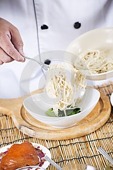 Chef holding the noodle from the bowl with fork