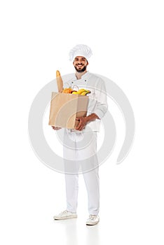 Chef holding shopping bag with baguette and fresh fruits on white background