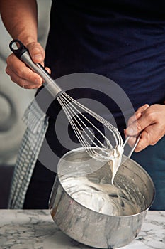 chef holding a white béchamel sauce on a whisk