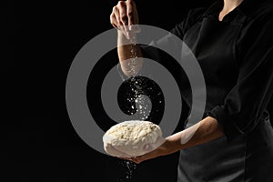 The chef holds the dough for bread, Italian pizza, focaccia. Freezing the flour in the air. Bakery, baking, cooking concept. On a