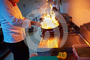 Chef in hotel kitchen prepare food with fire