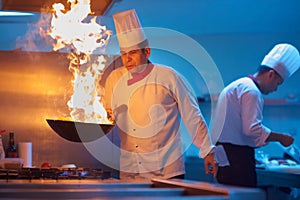 Chef in hotel kitchen prepare food with fire