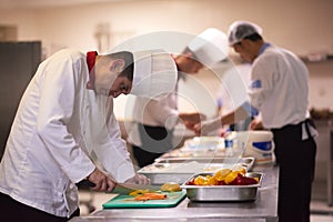 Chef in hotel kitchen slice vegetables with knife