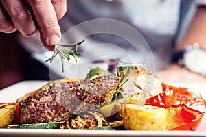 Chef in hotel or restaurant kitchen cooking only hands. Prepared beef steak with vegetable decoration