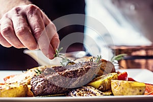 Chef in hotel or restaurant kitchen cooking only hands. Prepared beef steak with vegetable decoration