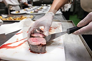 Chef in hotel or restaurant kitchen cooking, he is picking beef