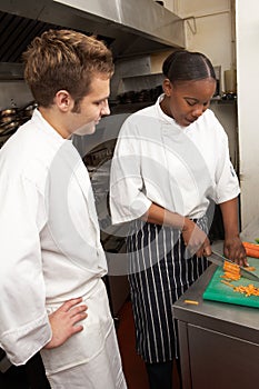 Chef Instructing Trainee In Restaurant Kitchen