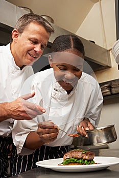 Chef Instructing Trainee In Restaurant Kitchen photo