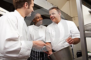 Chef Instructing Trainees In Restaurant Kitchen