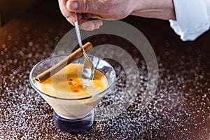 Chef introducing a spoon inside a glass of burnt cream