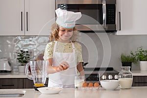 Chef kid boy baking on the kitchen. Child chef cook prepares food at kitchen. Kids cooking. Teen boy with apron and chef