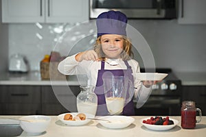 Chef kid preparing tasty food at kitchen. Child chef cook is learning how to make a cake in the home kitchen.
