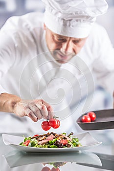 Chef in the kitchen of the hotel or restaurant decorates the food just before serving