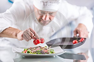 Chef in the kitchen of the hotel or restaurant decorates the food just before serving