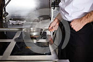 Chef at kitchen restaurant, preparing meal on stove