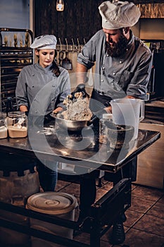 Chef kneading dough in the kitchen. Chef teaching his assistant to bake the bread in the bakery.