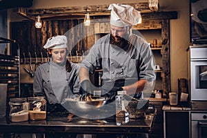 Chef kneading dough in the kitchen. Chef teaching his assistant to bake the bread in the bakery.