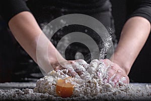 A chef is kneading dough using eggs, kitchen dark background