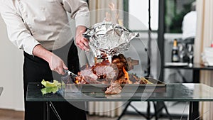 Chef with knife cuts baked Turkey on a platter in the fire. Roast Turkey.