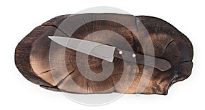 Chef knife on oak cutting board, burnt log slice cutted tree trunk isolated on white background, top view