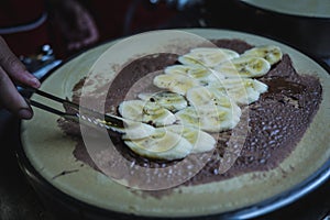 Chef makes chocolate banana crepe on hot pan at bangkok