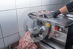 Chef makes minced pork meat using a meat grinder.