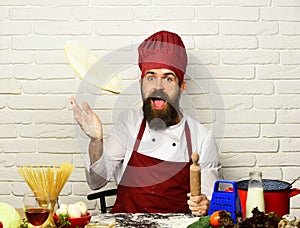 Chef makes pizza. Man with beard throws pizza dough up