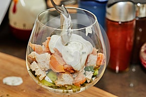 Chef makes Summer salad in glass of salmon, cucumbers, croutons, herbs and fresh cream, Elegant Summer Fusion