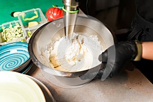 Chef making cheese mix for cheese pancake at restaurant. Blender whips the cottage cheese. Cheesecake preparing.