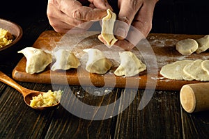 The chef is making dumplings with his hands. Step-by-step process of preparing homemade dumplings filled with mashed potatoes on a