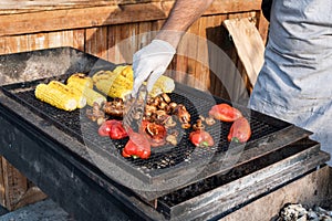 Chef making grilled vegetables outdoor on open kitchen international street food festival event.