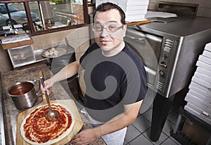 Chef making a pizza spreading sauce
