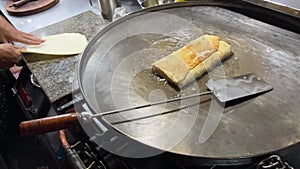 A chef making street food with wide frying pan on open kitchen