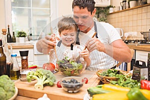 Chef man cooking on the kitchen with little son.