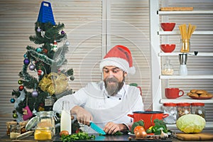 Chef man in santa claus hat cooking.