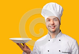 Chef Man Serving Dish Holding Empty Plate Over Yellow Background