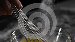 Chef mixes the eggs with the sugar black background